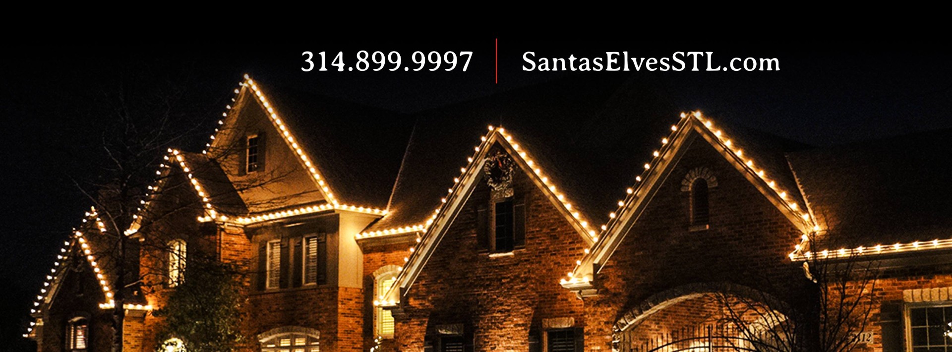 Brick home with peaked rooflines outlined in warm white Christmas lights