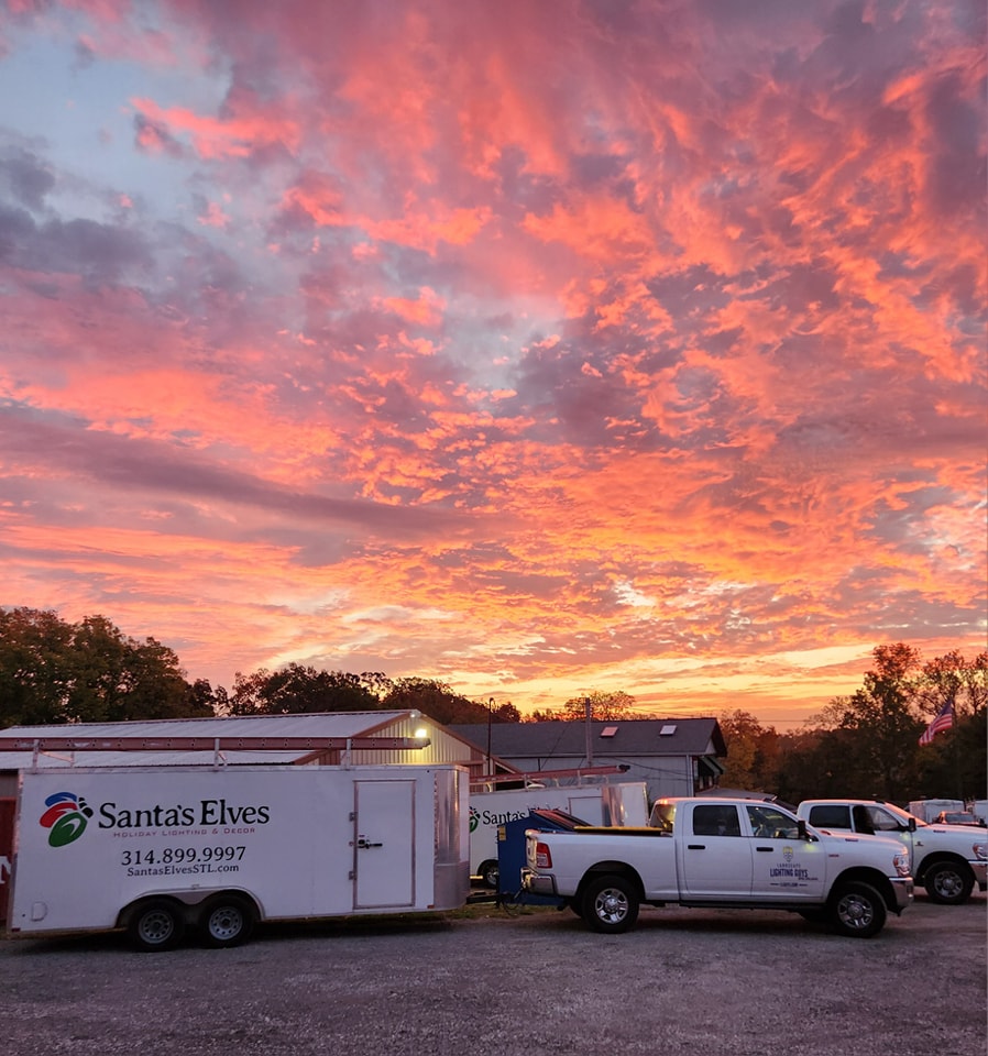 Santa's Elves trailer and trucks at the St. Louis facility under a sunset sky